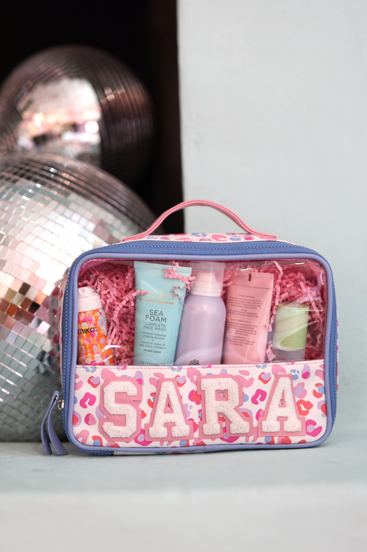 Personalized pink makeup bag containing skincare products, with clear window and playful leopard print design.