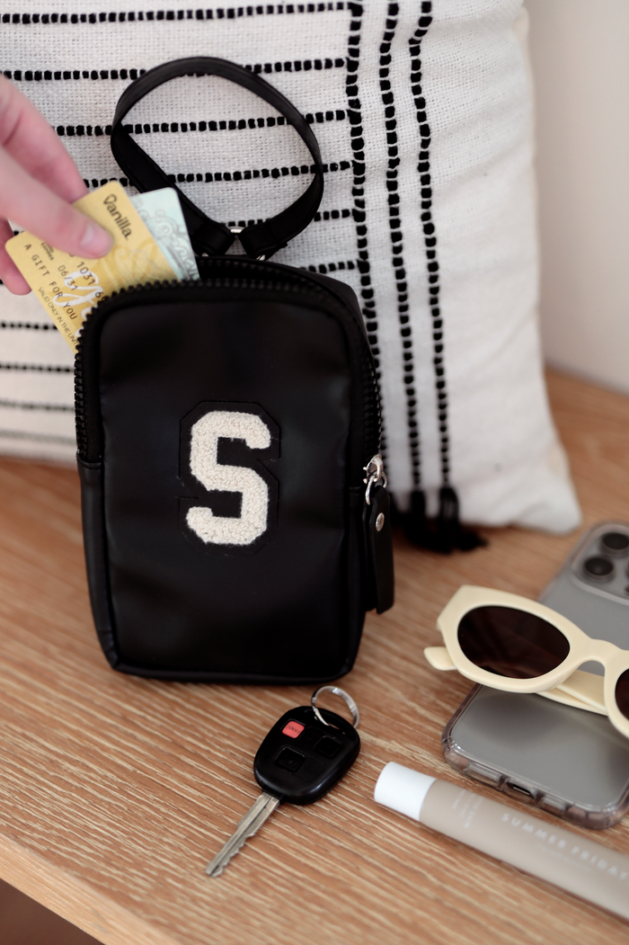 Small black leather pouch with letter 'S', perfect for cards and keys, stylish and compact for everyday use.