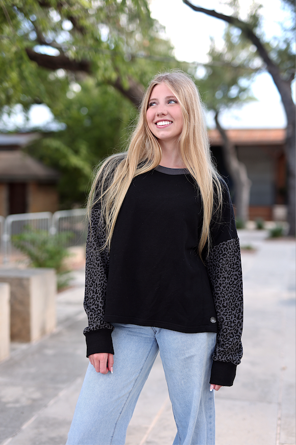 Women's black sweatshirt with leopard print sleeves, made from soft cotton for casual wear.