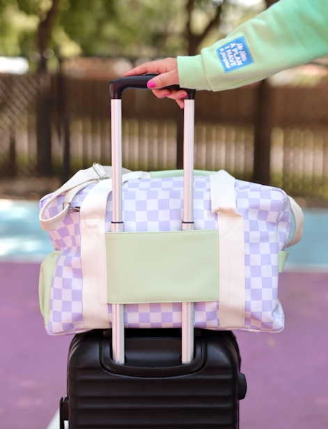 Lavender checkered duffel bag with mint green accents, ideal for travel and easily attached to luggage.