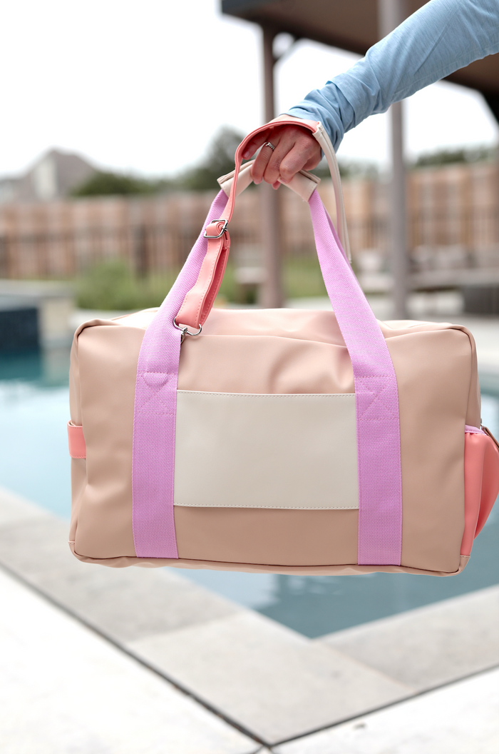 Stylish beige and pink duffel bag with adjustable straps, perfect for gym or travel.