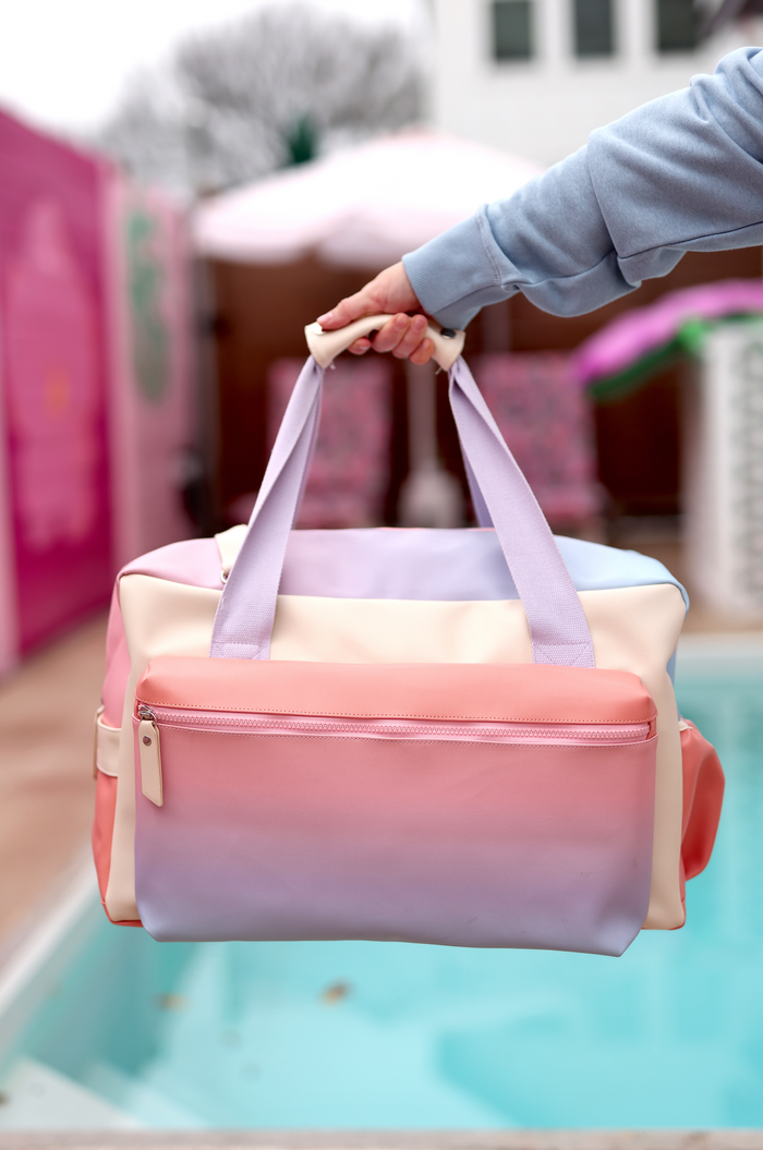 Stylish gradient travel bag in pastel pink and purple, durable material, with a spacious zippered compartment.