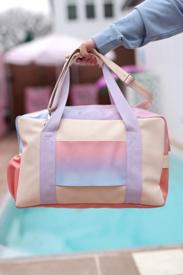 Stylish pastel gradient duffle bag with dual handles and adjustable strap, perfect for travel or gym.