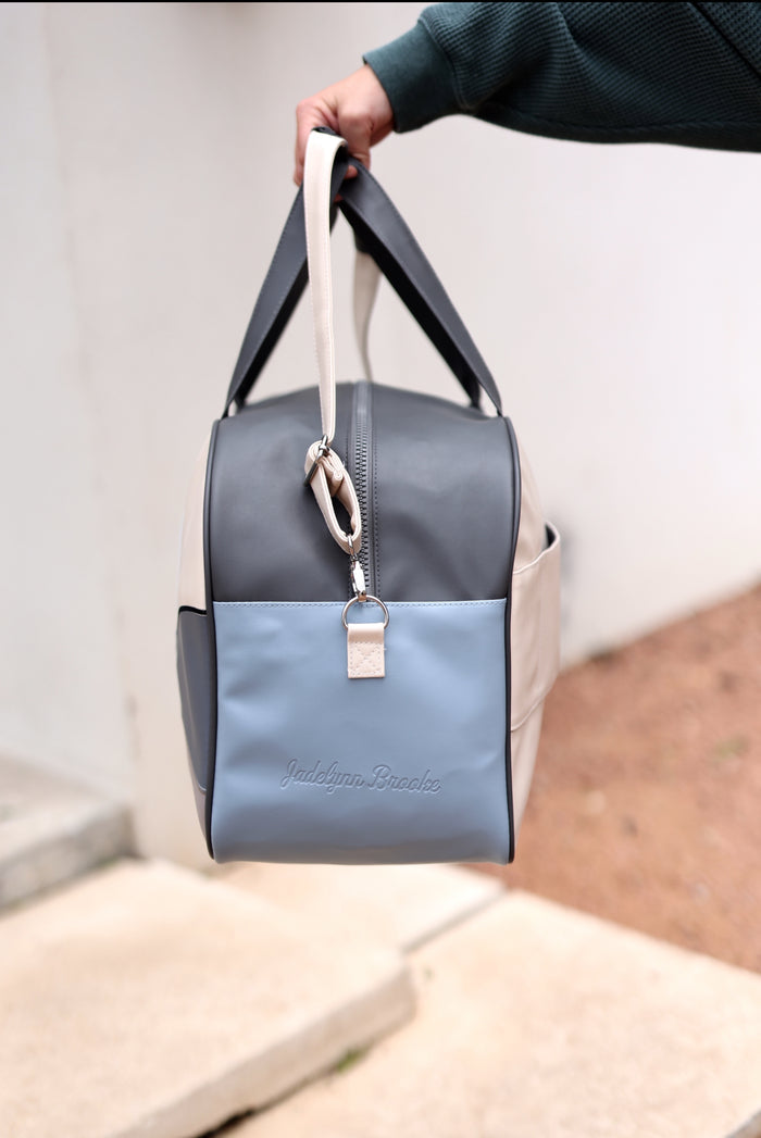 Stylish gray and blue leather duffel bag with top handles and zipper, ideal for travel and daily use.