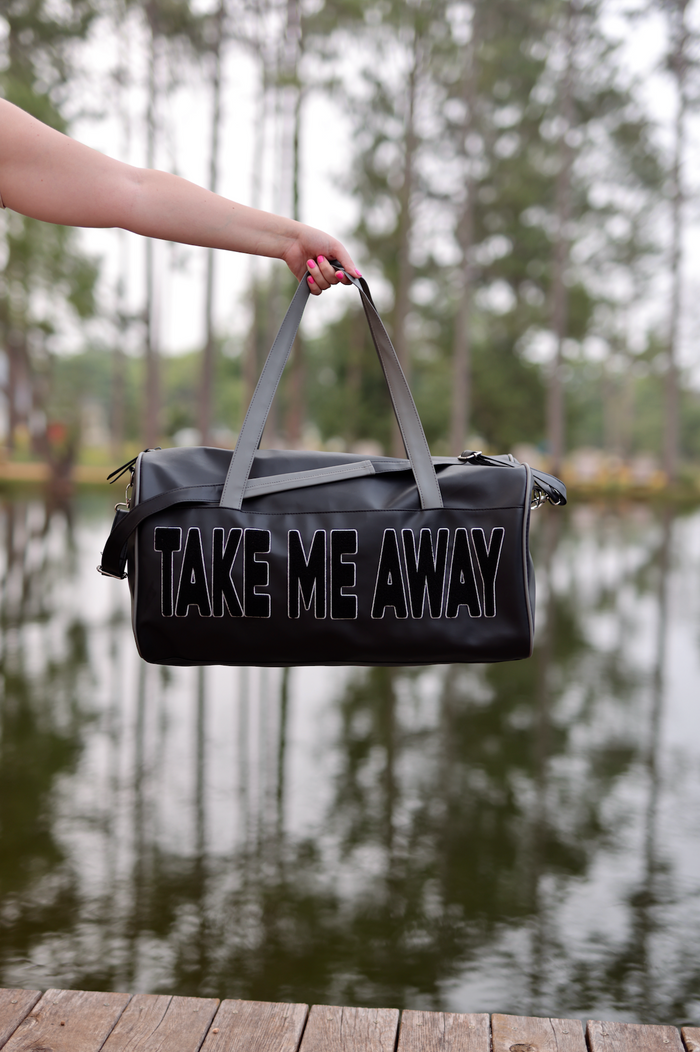Black travel duffel bag with 'TAKE ME AWAY' text, durable material, perfect for getaways.