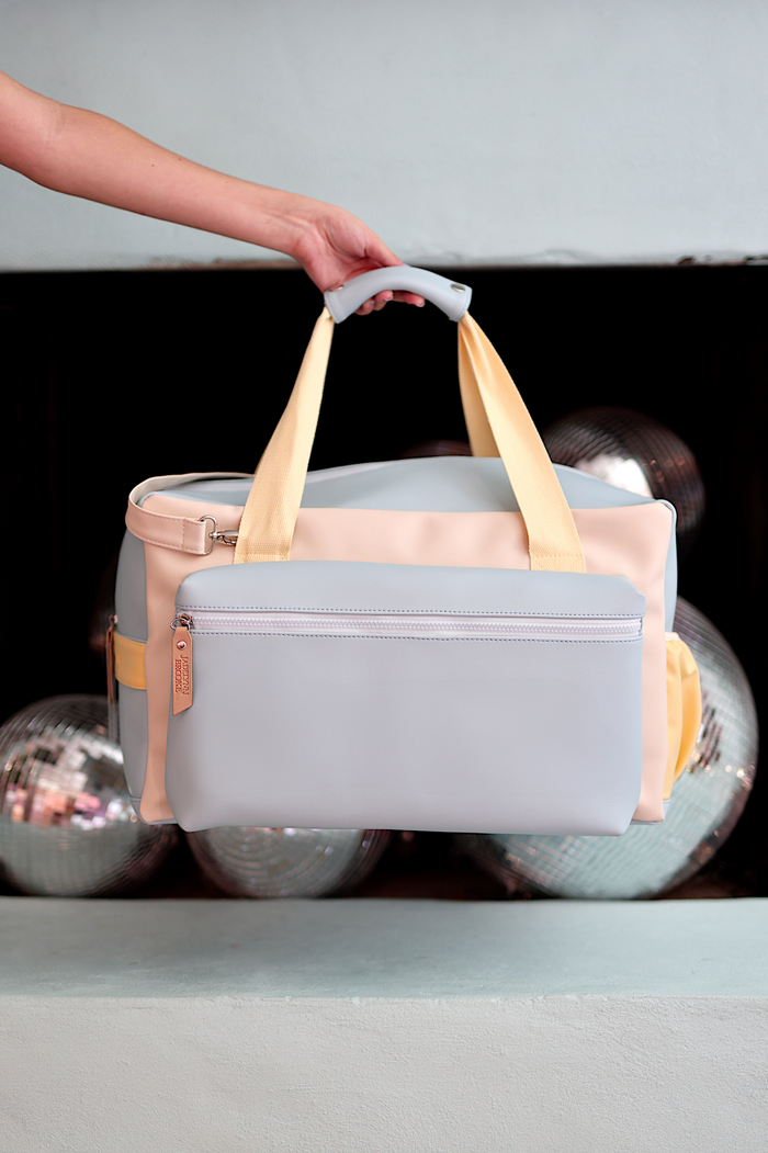 Stylish lightweight duffle bag in gray and pastel yellow, featuring a zippered front pocket and durable handles.