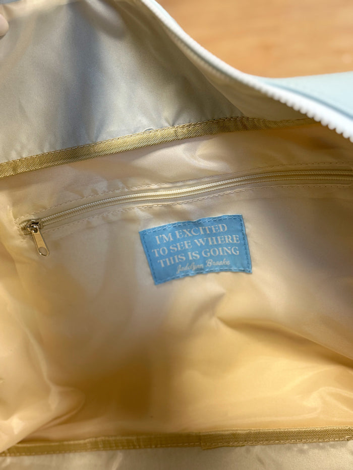 Interior view of a light-colored bag featuring a zip pocket and a motivational label.