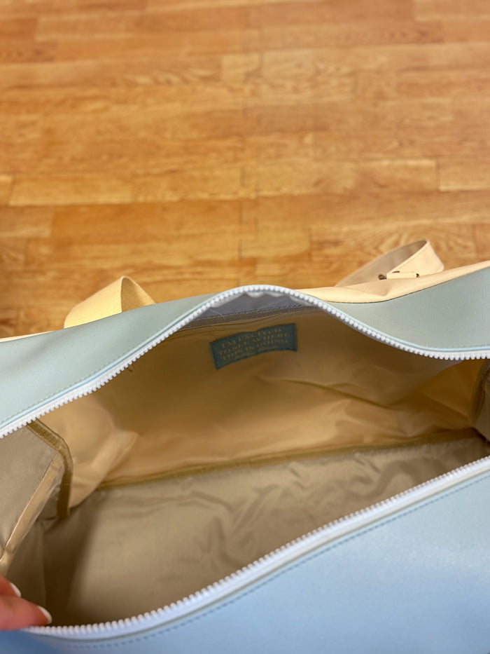 Top view of a spacious light blue tote bag with beige straps and a smooth interior lining.