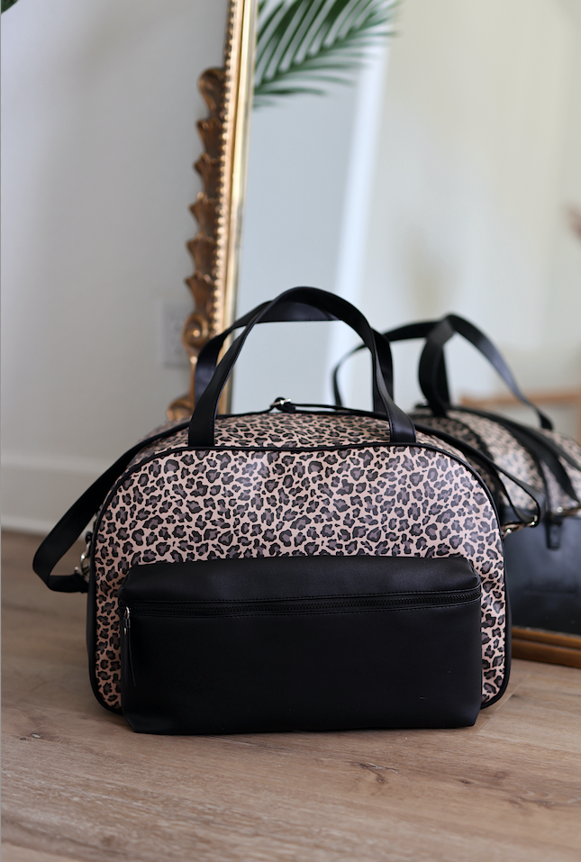Stylish leopard print duffel bag with black accents, made from durable materials, perfect for travel.