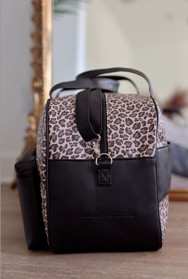 Stylish leopard print backpack with black leather accents, featuring sturdy zippers and adjustable straps.