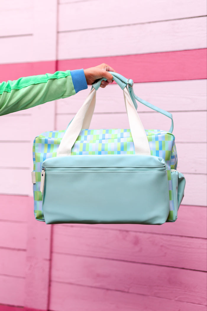 Colorful patterned duffel bag in mint and blue hues with a spacious design and removable shoulder strap.