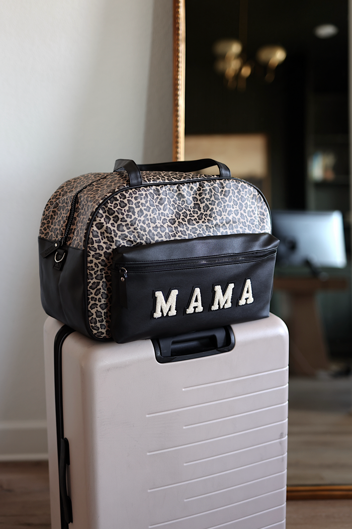 Leopard print duffel bag labeled 'MAMA' on top of a suitcase indoors.