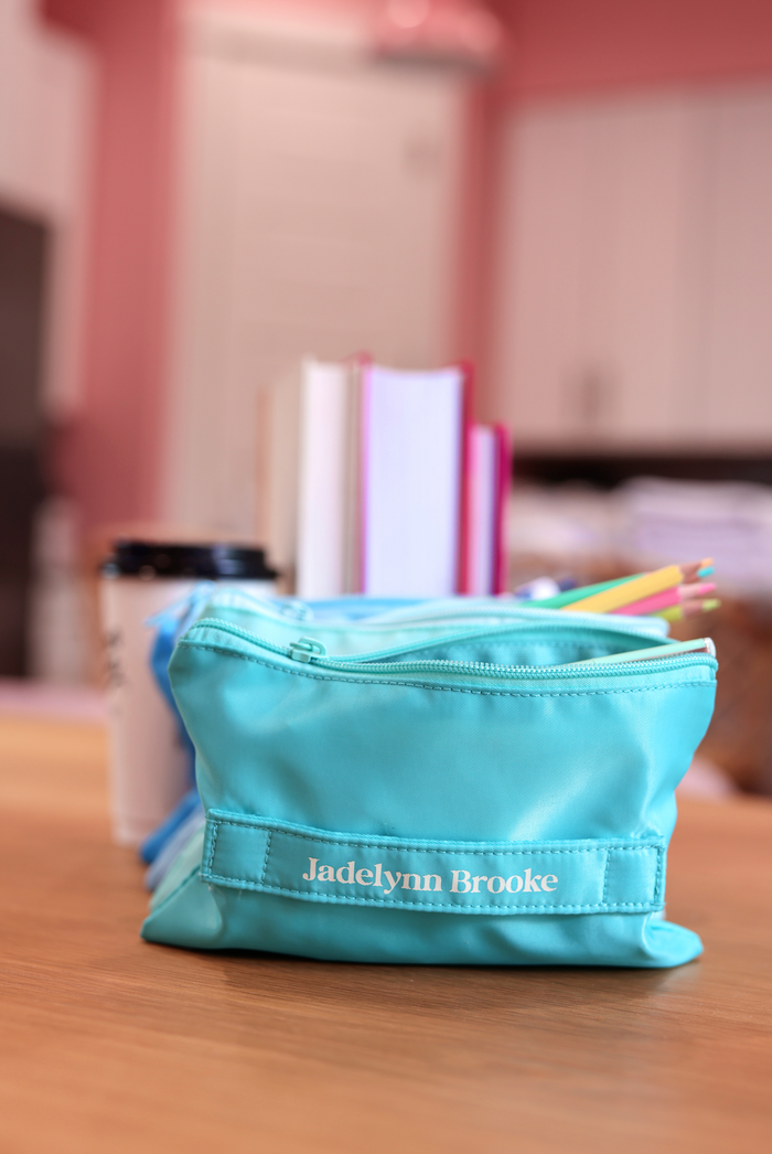 Light blue polyester makeup bag with zipper and 'Jadelynn Brooke' branding, ideal for travel and organization.