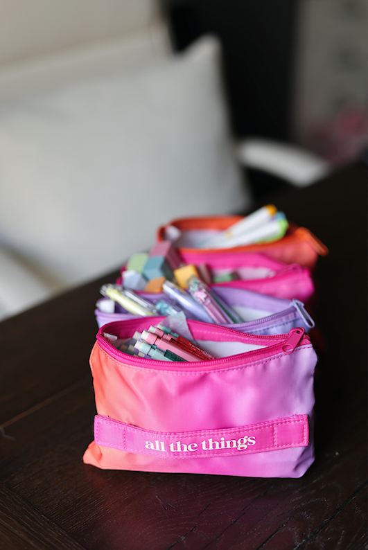 Colorful nylon pencil pouch in pink gradient, filled with pens and stationery, labeled 'all the things'.