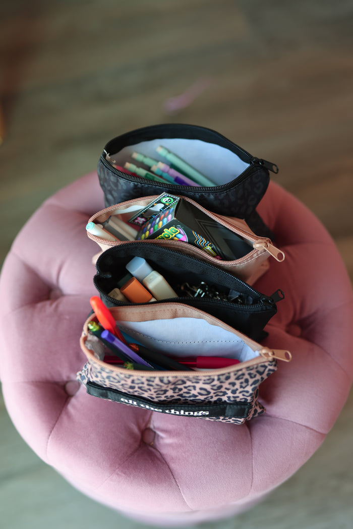 Small pouches with stationery items on a pink cushion