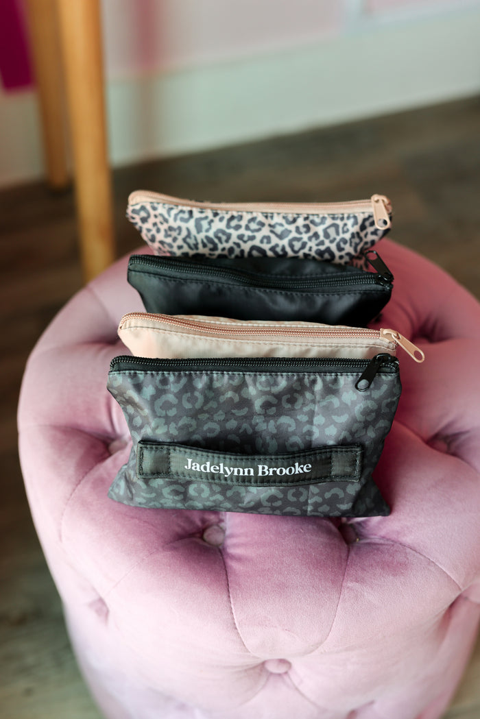 Four small zippered pouches stacked on a pink cushion with 'Jadelynn Brooke' branding.