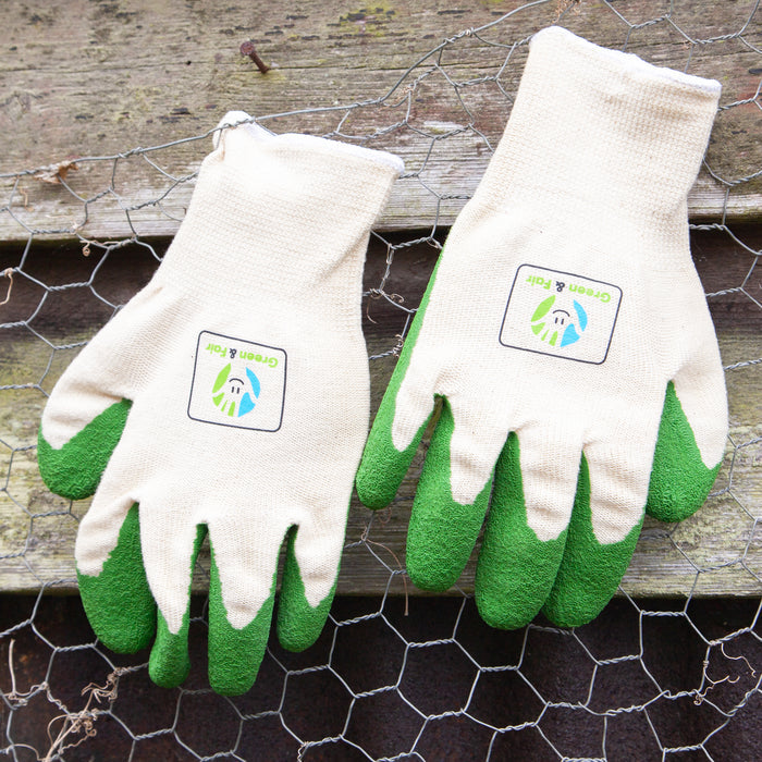 Pair of gardening gloves with green fingertips on a wooden surface