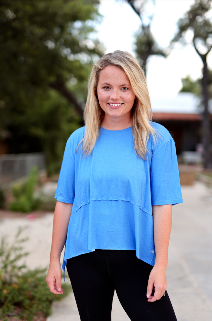 Relaxed fit blue top made from soft cotton, featuring short sleeves and layered design.
