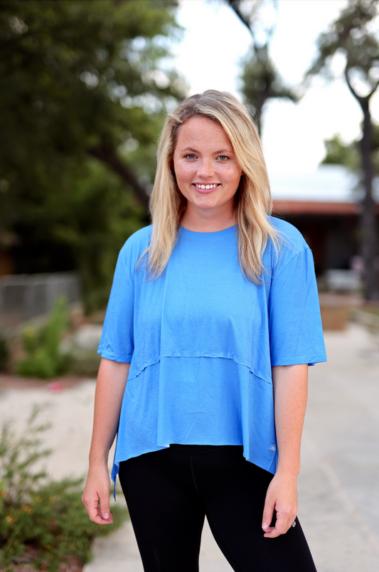Relaxed fit blue top made from soft cotton, featuring short sleeves and layered design.