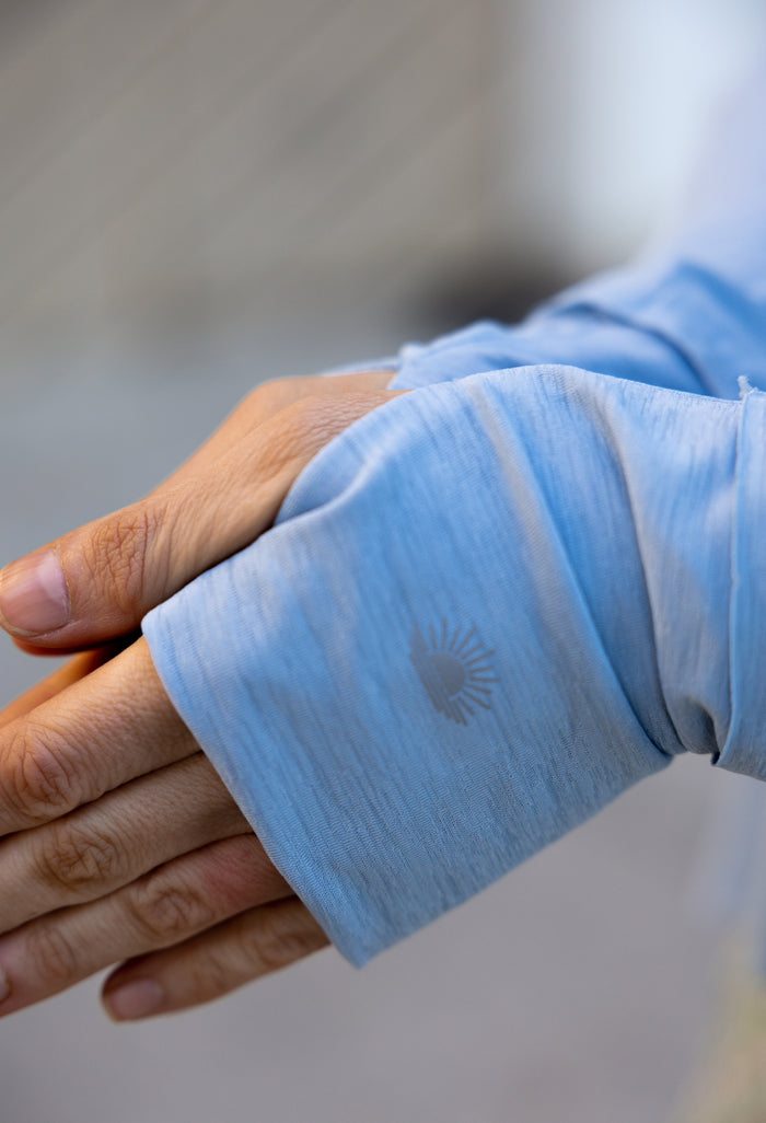 Light blue long sleeve shirt made from breathable fabric with sun logo detail on the cuff.
