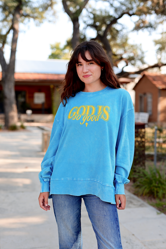 Light blue oversized sweatshirt with 'GOD IS so good' graphic, perfect for casual wear.
