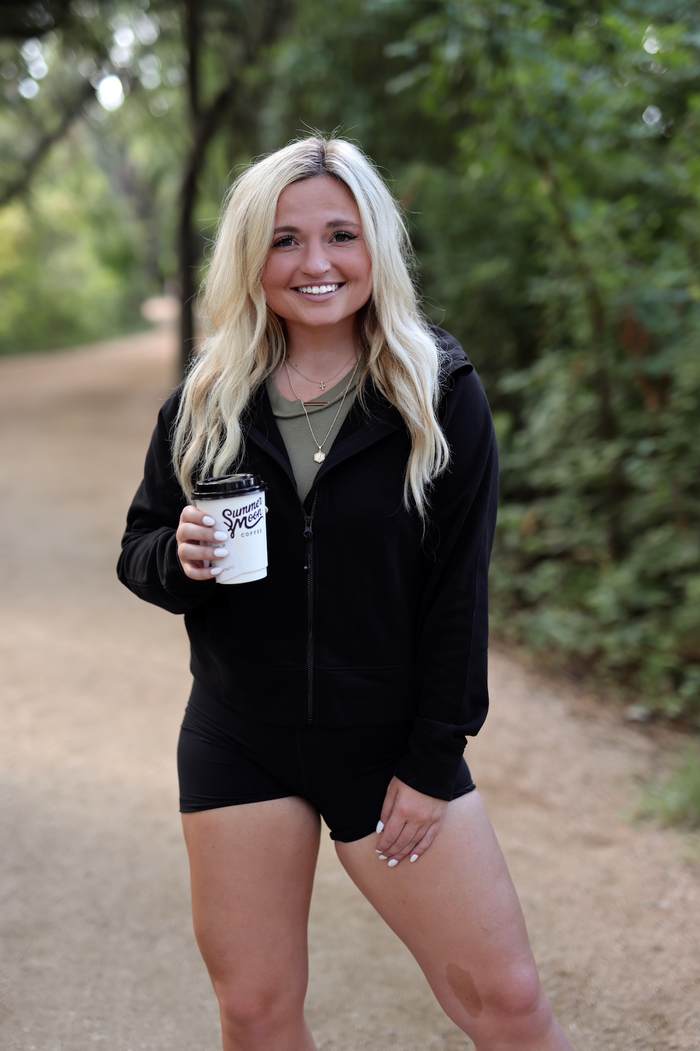 Stylish black zip-up hoodie with a casual look, paired with black shorts and coffee cup.