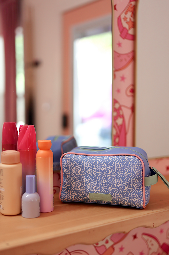 Blue floral cosmetic bag with pink accents, perfect for organizing makeup and toiletries.