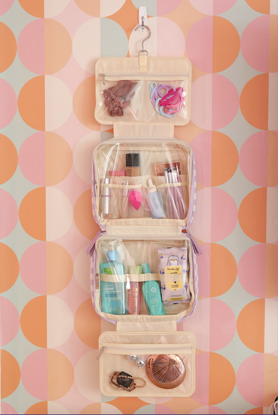 Hanging cosmetic organizer in cream with compartments for toiletries and accessories.
