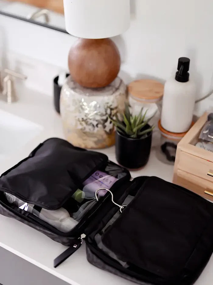 Black cosmetic bag with organized compartments for toiletries and skincare, perfect for travel.