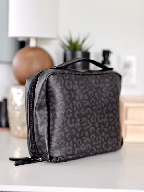 Stylish black leopard print cosmetic bag with handle and zipper closure, perfect for travel and organization.