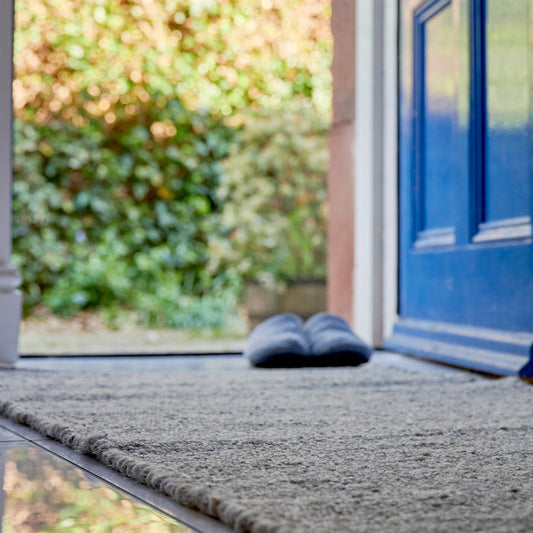 Grey wool Herdwick rug on white tiled floor with grey wool slippers