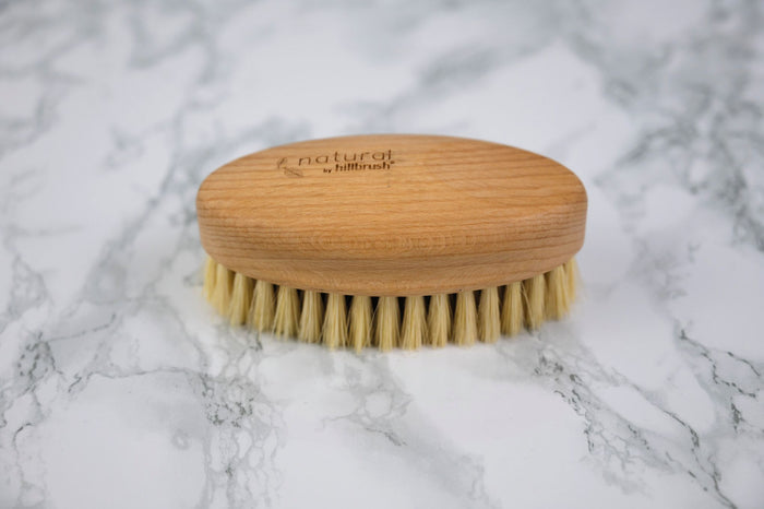 FSC and natural bristle vegetable scrubbing brush on marble background