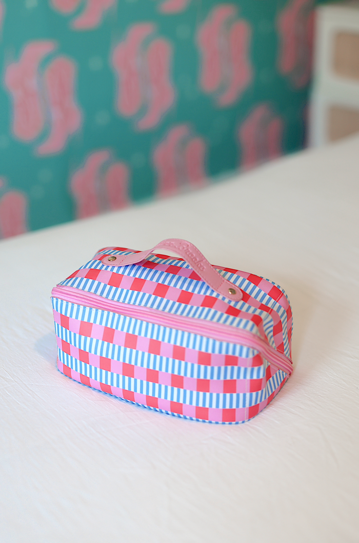 Colorful striped cosmetic bag in pink and blue, featuring a zipper and sturdy handle for easy carrying.