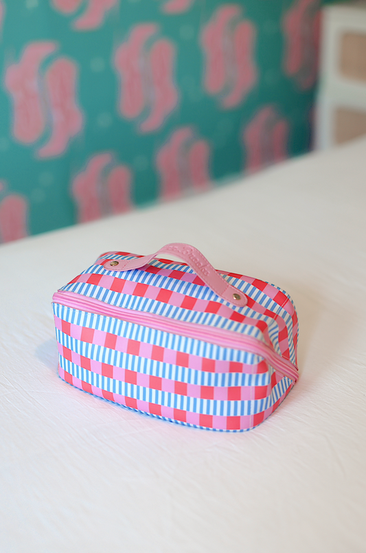 Colorful striped cosmetic bag in pink and blue, featuring a zipper and sturdy handle for easy carrying.