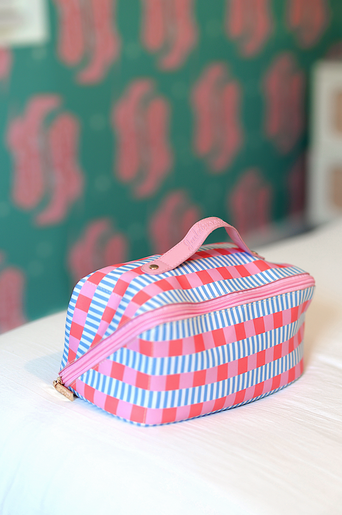 Colorful striped cosmetic bag in pink and blue with zipper closure and handle, perfect for travel.
