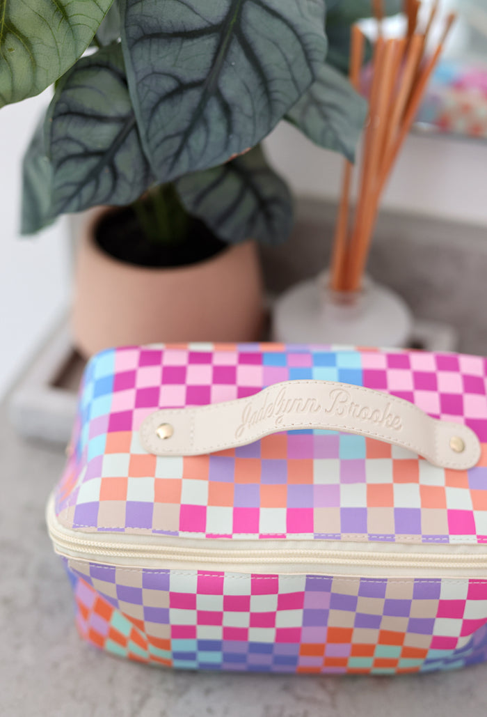 Colorful checked cosmetic bag by JadeLynn Brooke, featuring a cream handle and zip closure.