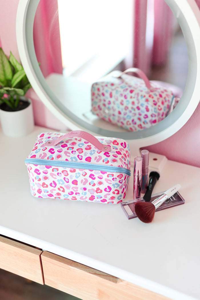 colorful cheetah makeup bag on a vanity with mirror and makeup items