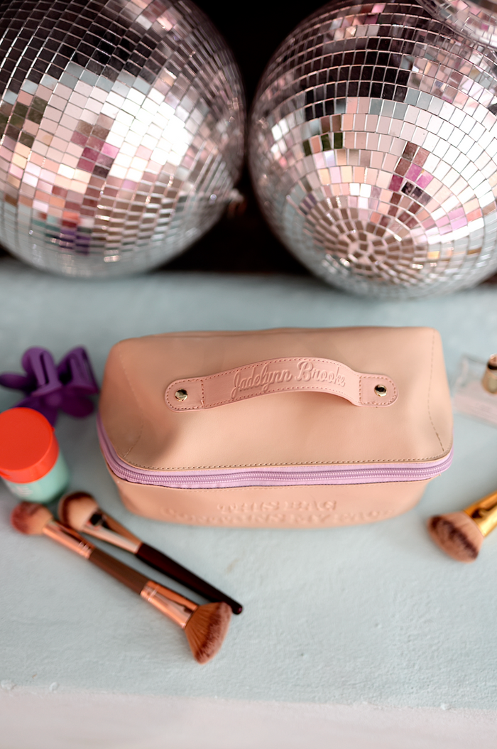 Pink makeup bag by JadeLynn Brooke, featuring a stylish design and zipper closure.