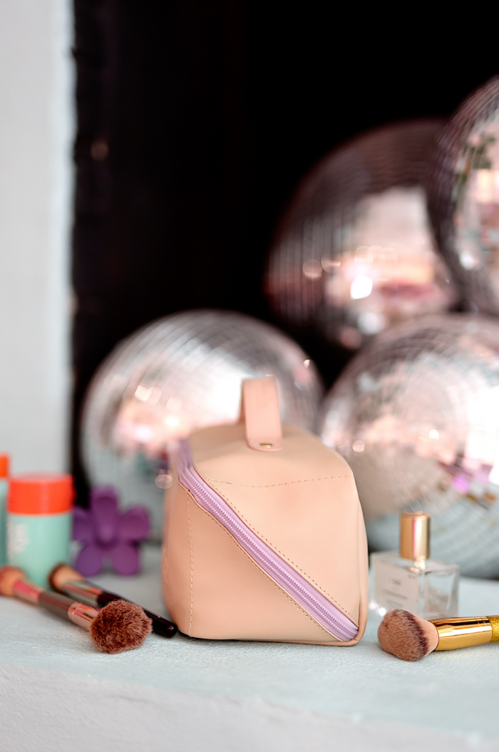 Stylish peach makeup bag with purple zipper, perfect for holding brushes and cosmetics.