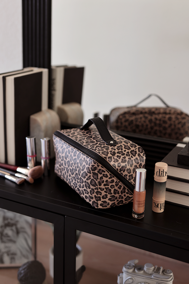 Stylish leopard print makeup bag with black zipper and handle, ideal for cosmetics storage.