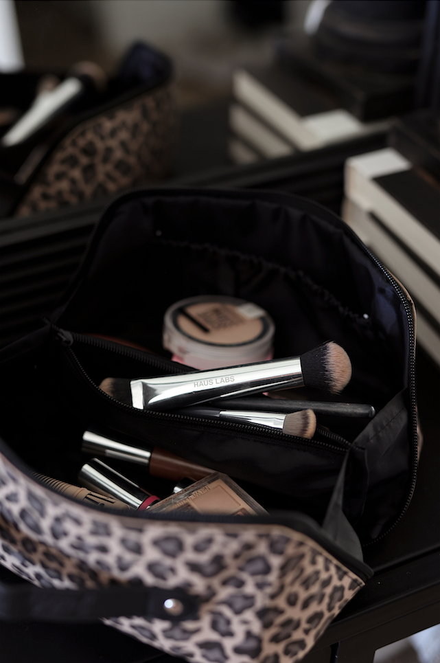 Leopard print makeup bag with brushes, cosmetics, and a sleek interior design.