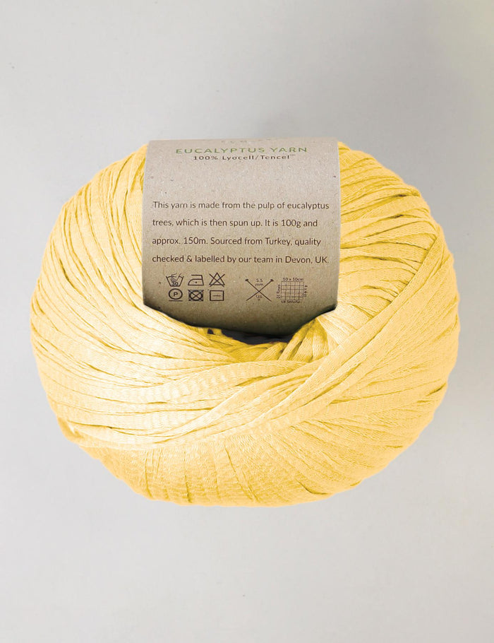 Yellow yarn ball with a label on a gray background
