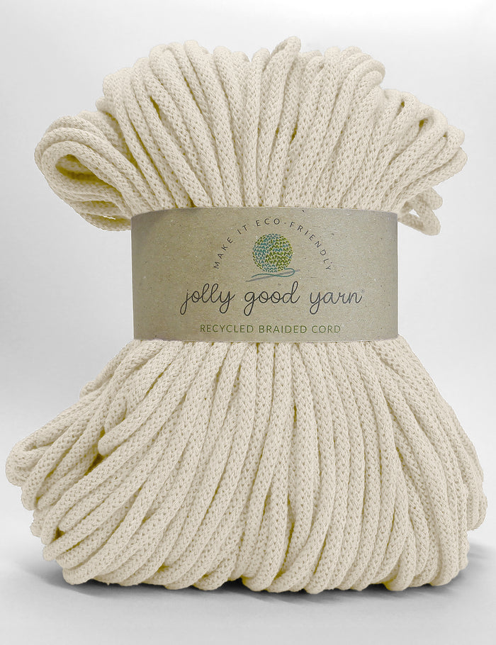 A bundle of off-white braided cord yarn wrapped with a paper label that reads 'jolly good yarn' and 'RECYCLED BRAIDED CORD' on a white background.