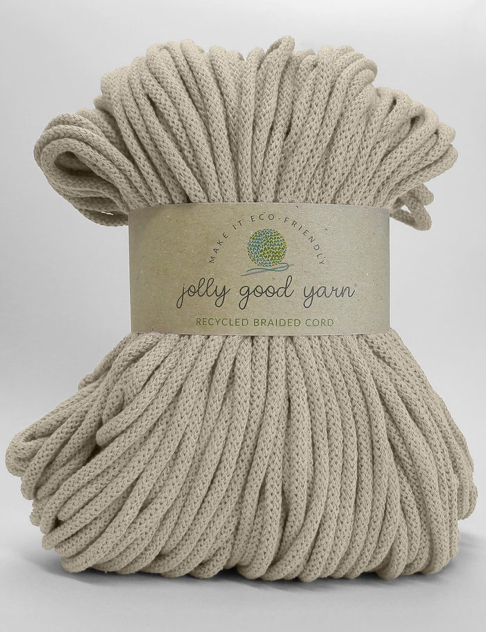 A large bundle of beige braided cord yarn wrapped with a paper label that reads 'jolly good yarn' and 'RECYCLED BRAIDED CORD' on a light grey background.