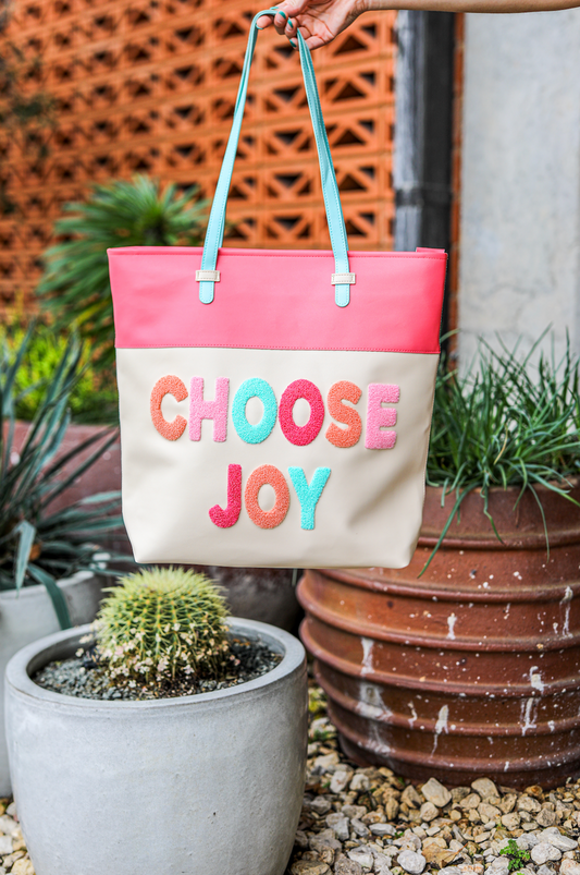 Colorful 'Choose Joy' tote bag with pink and cream faux leather, ideal for everyday use.