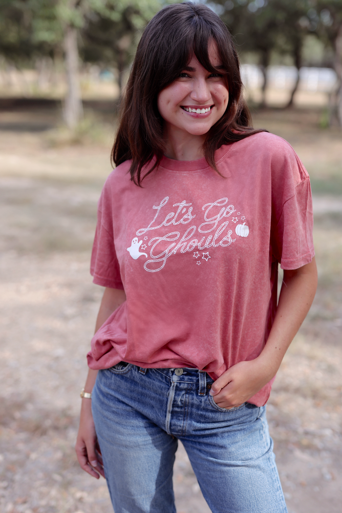 Woman wearing a pink t-shirt with text and graphics outdoors