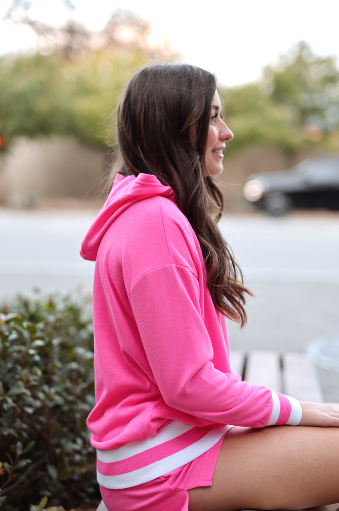 Bright pink hoodie with white stripes, perfect for casual outfits and comfortable wear.