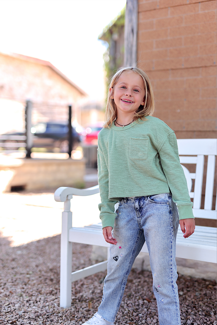 Light green cropped sweatshirt for kids with front pocket, paired with embroidered light blue jeans.