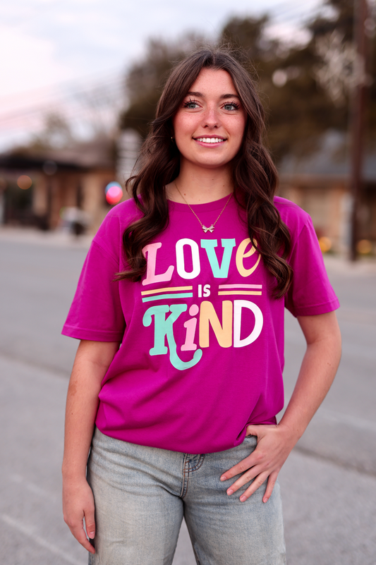 Pink graphic t-shirt featuring 'Love is Kind' print, perfect for casual style and comfort.