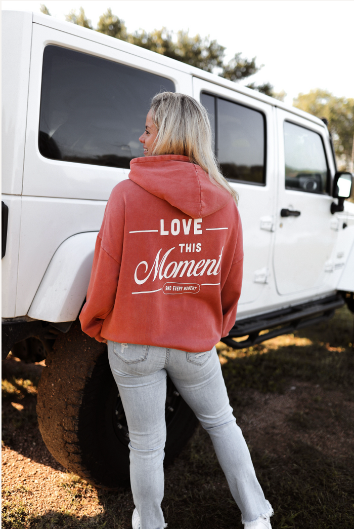 Pink pullover hoodie with 'Love this Moment' graphic, casual style for women, perfect for outdoor wear.